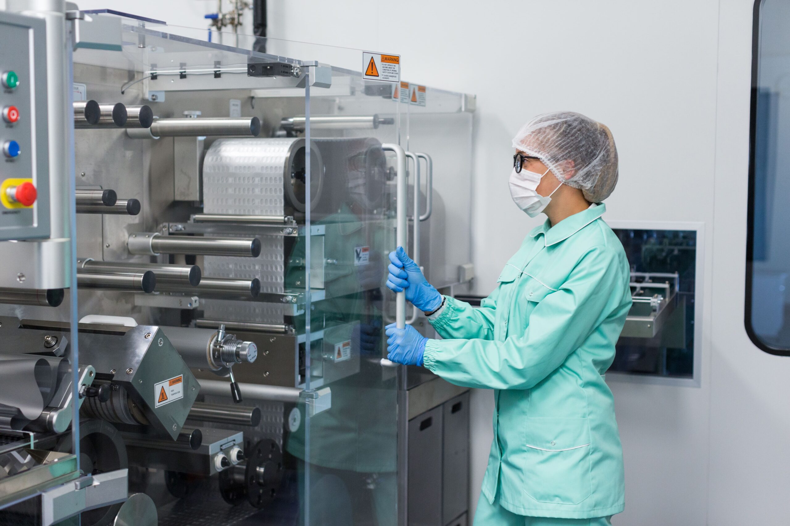 caucasian-factory-worker-blue-lab-suit-work-with-machine-machine-with-glass-panels-min