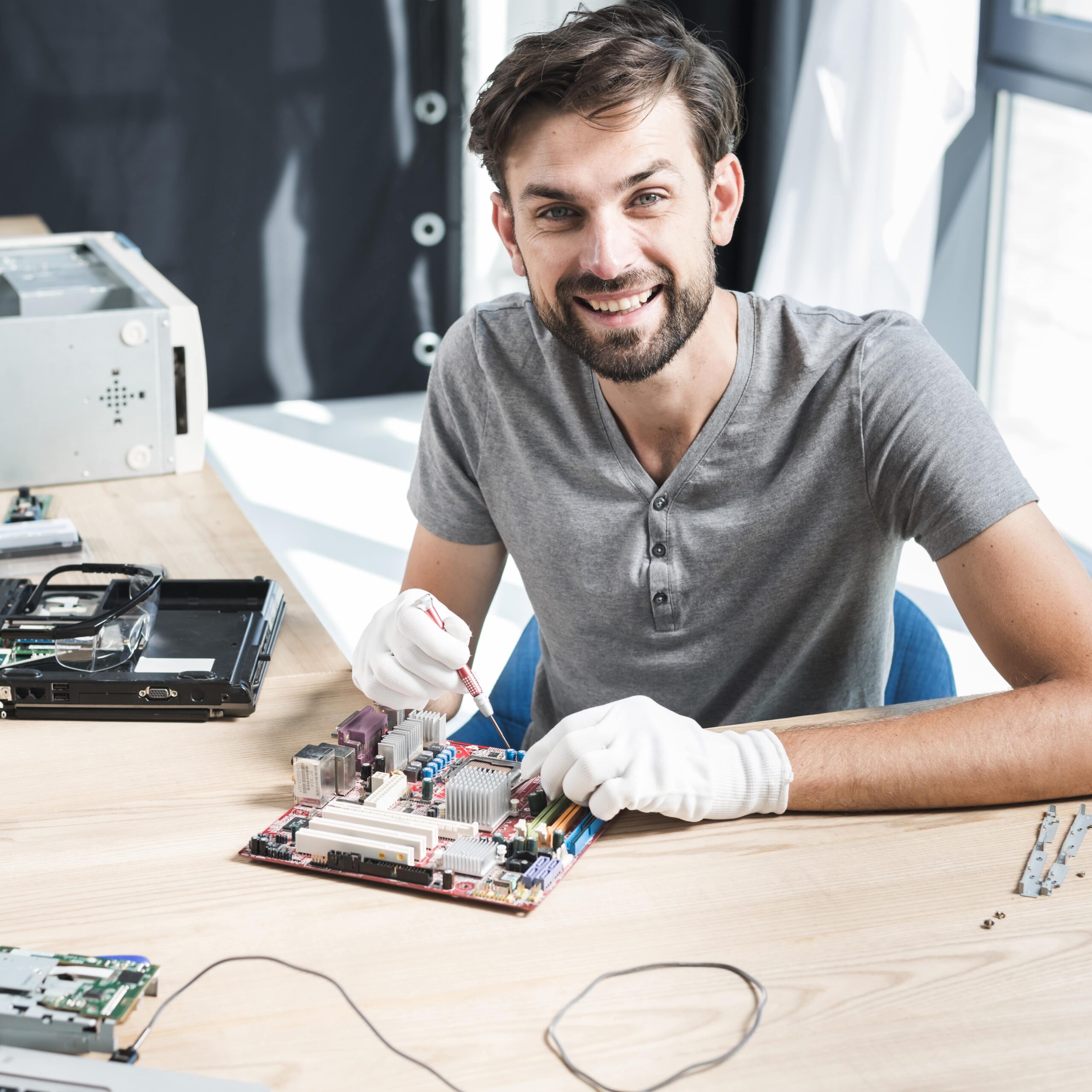 portrait-smiling-male-technician-repairing-computer-motherboard-min